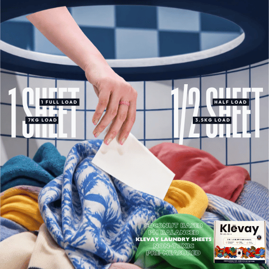 Hand dropping a Klevay detergent sheet onto a pile of colourful laundry, one sheet per load